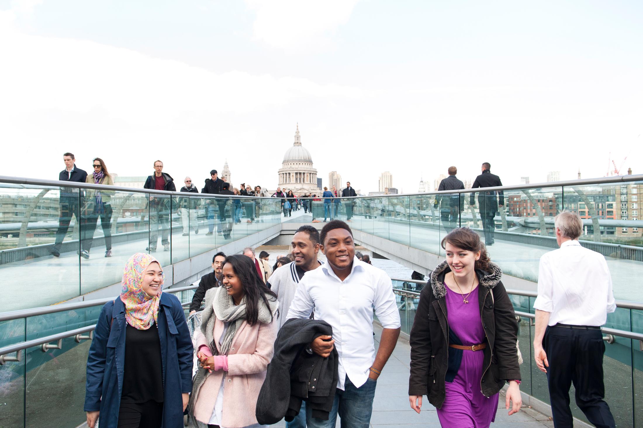 A diverse group of individuals walking on a bridge, showcasing unity and camaraderie in their journey.