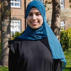 Duha stood on campus on a sunny day with campus building in background