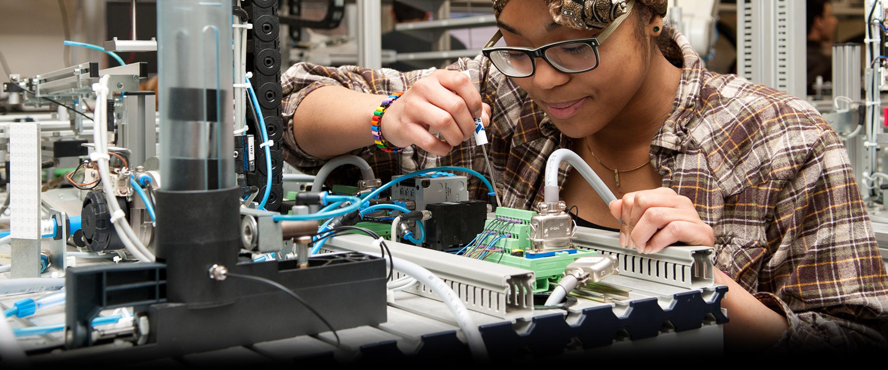 Female student working on engineering equipment in the MDX mechatronics lab