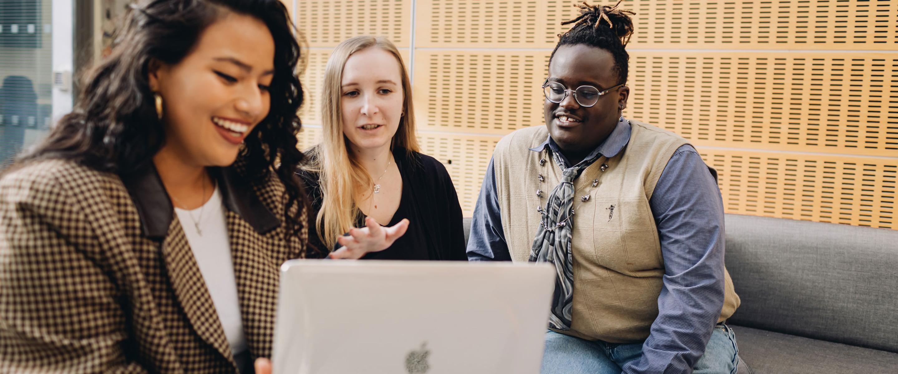 Mixed group of diverse people talking in front of a laptop.