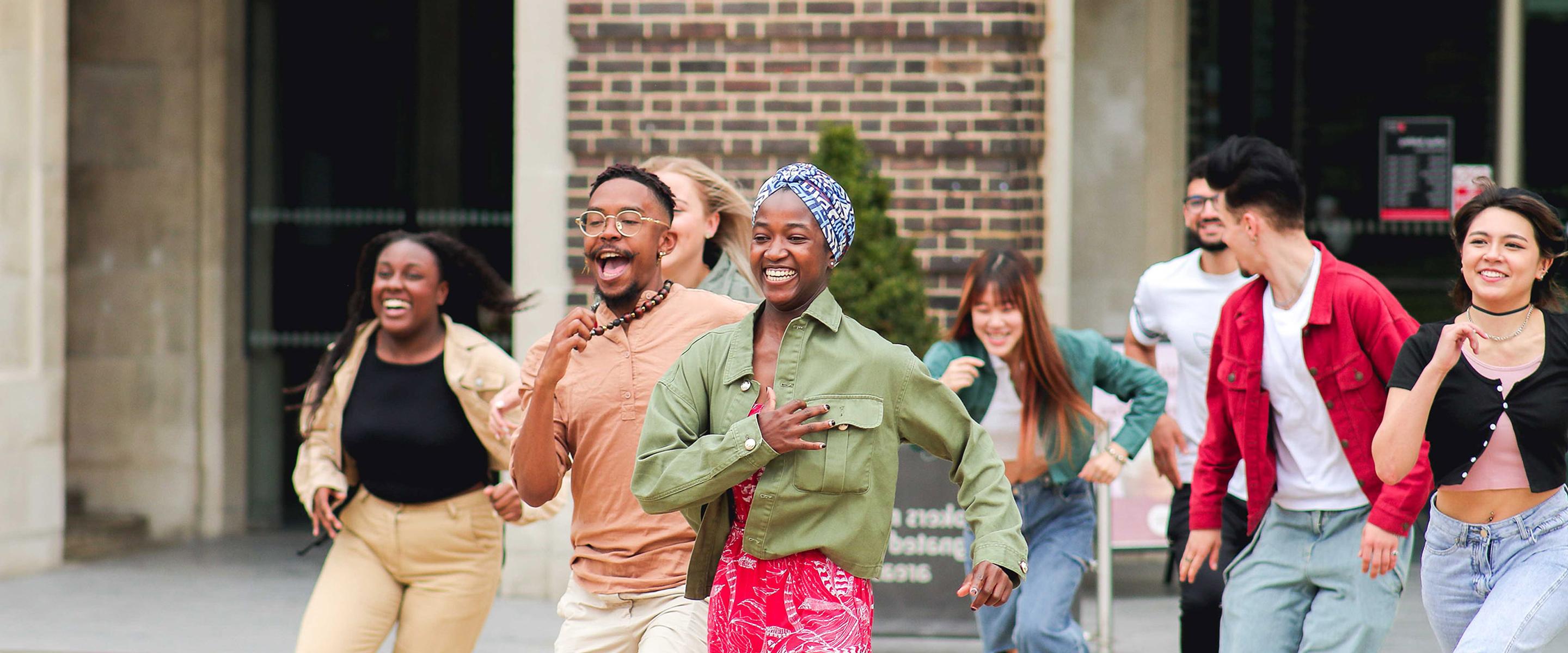 Excited students running in front of a campus building