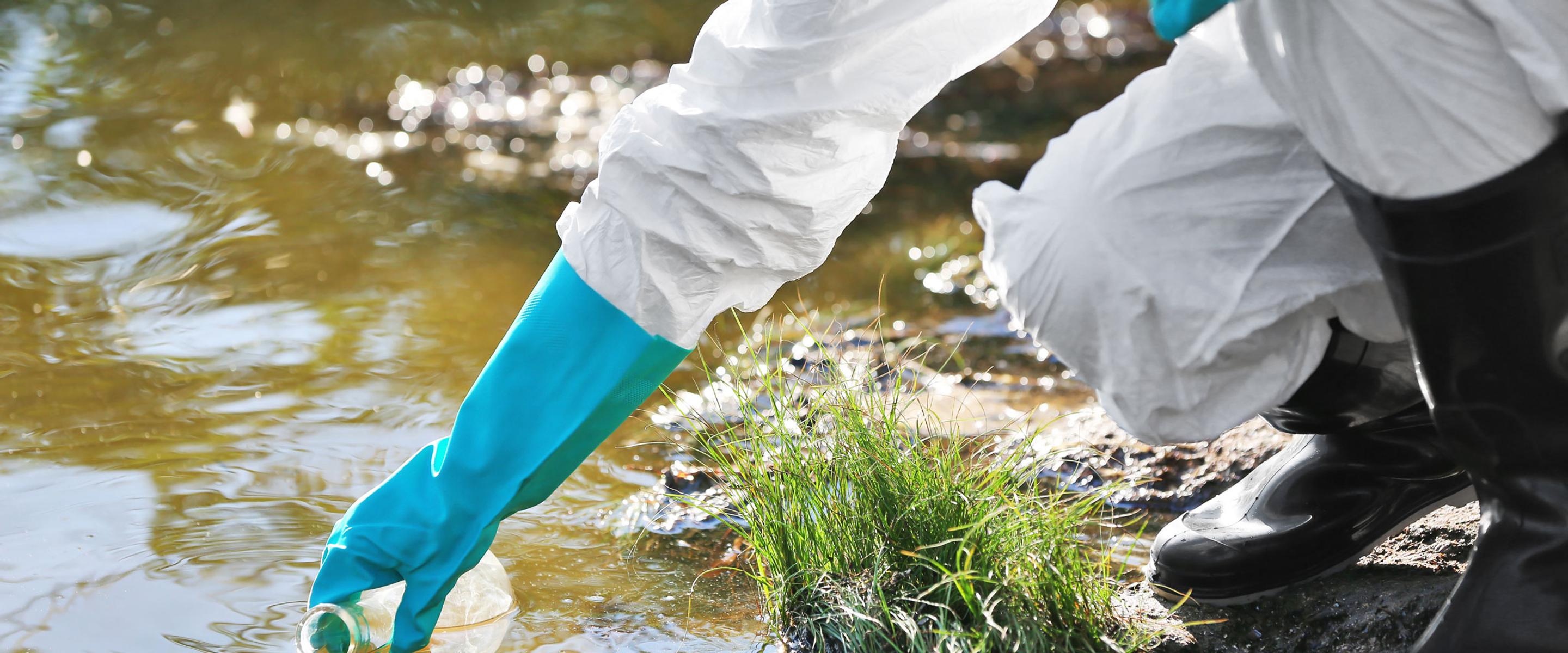 environmental health practitioner in a white coat and rubber gloves is sampling the water
