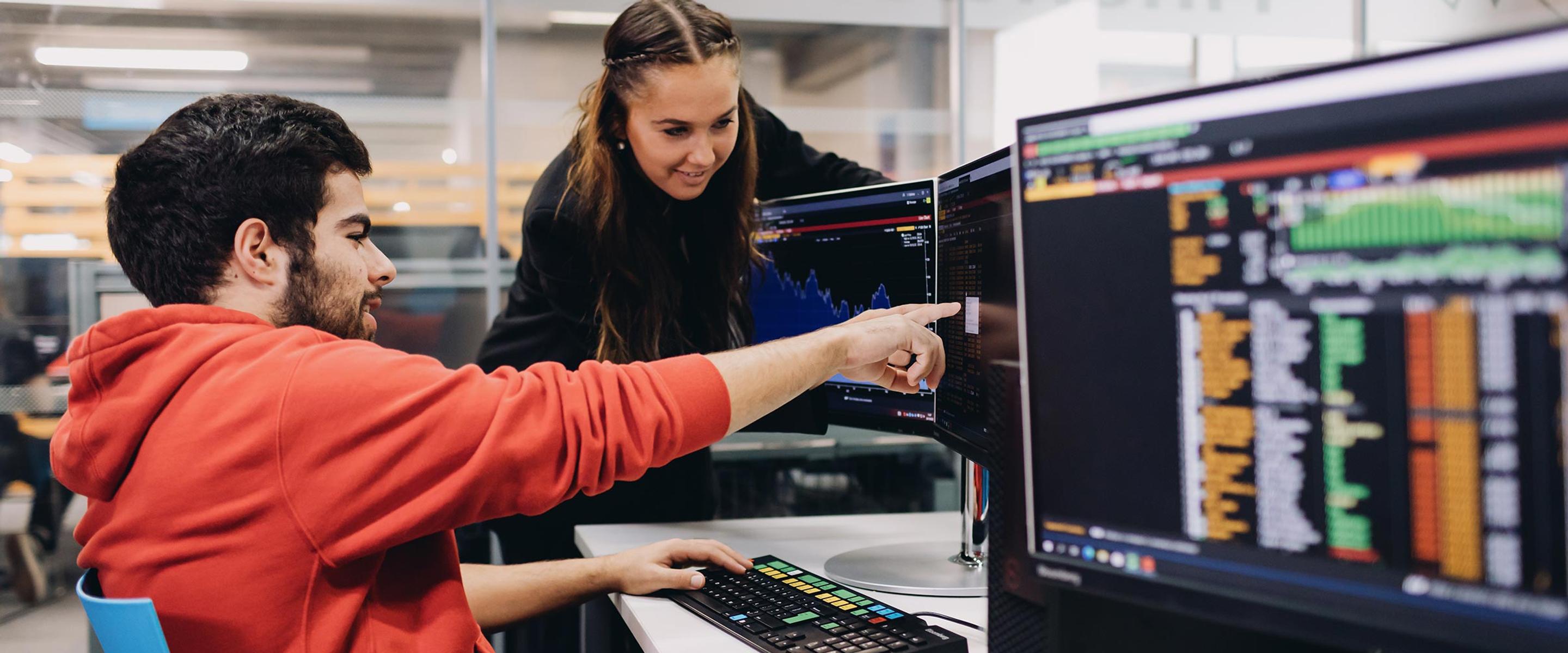 Two students look at financial figures on the computer