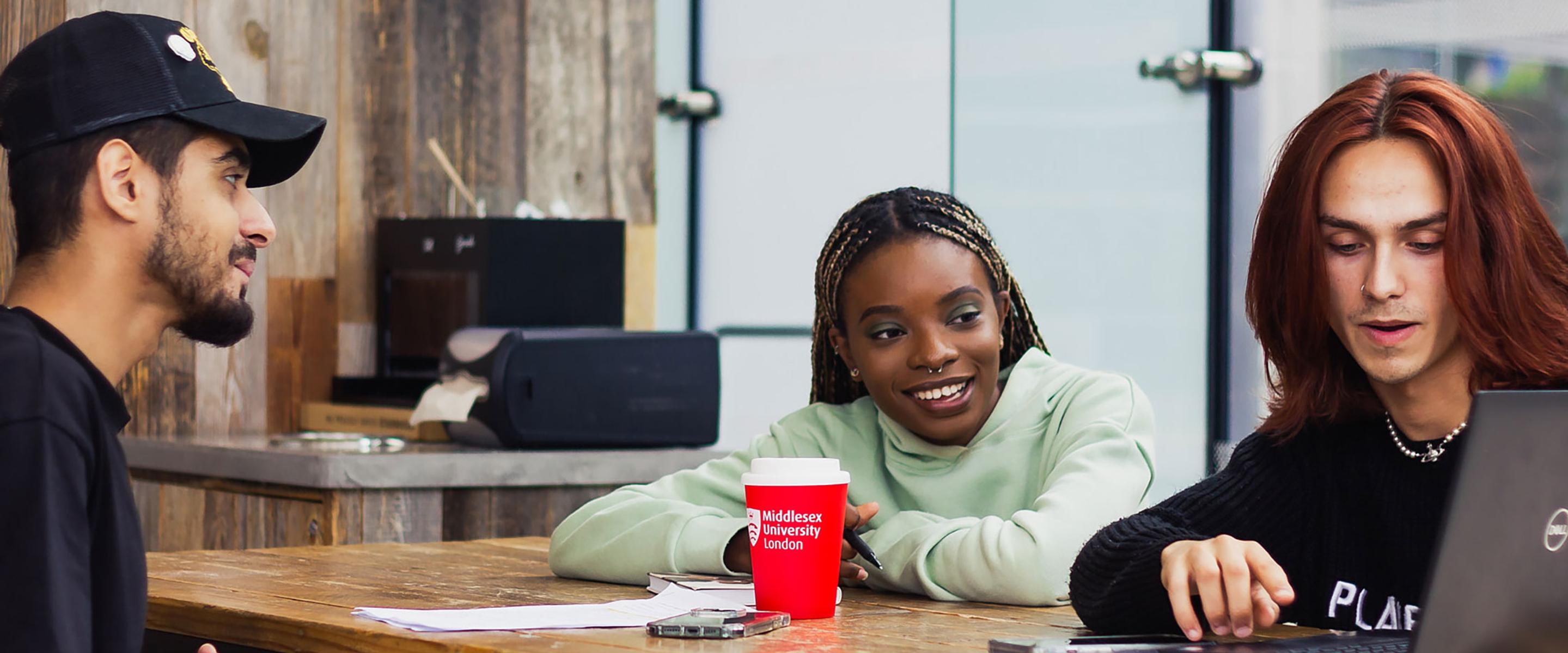 Students at cafe table, looking at laptop