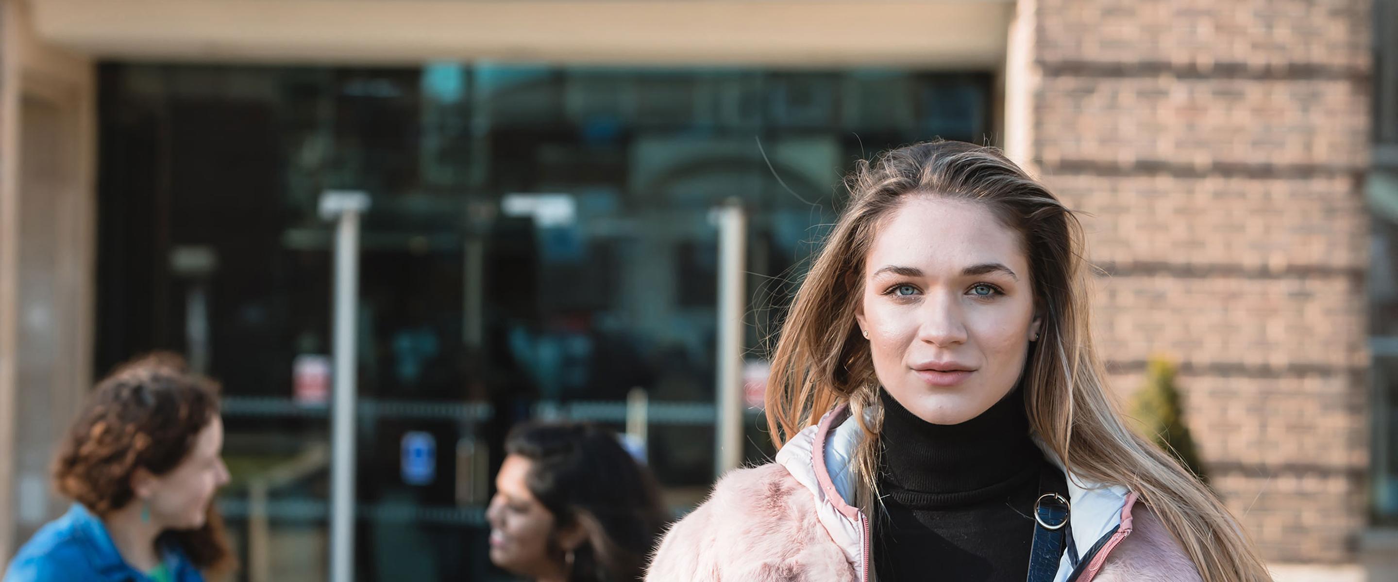 Female student in front of a red brick building