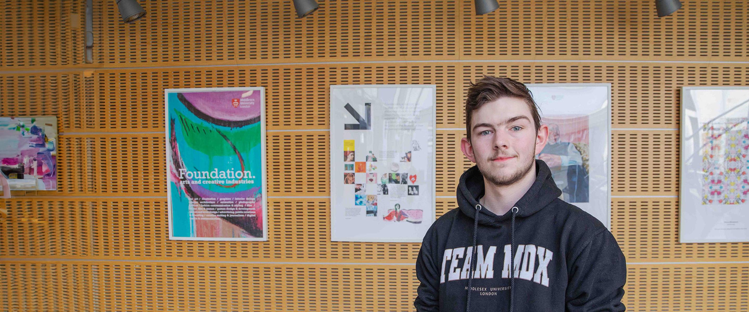 Toney - clearing student stood in front of gallery of work
