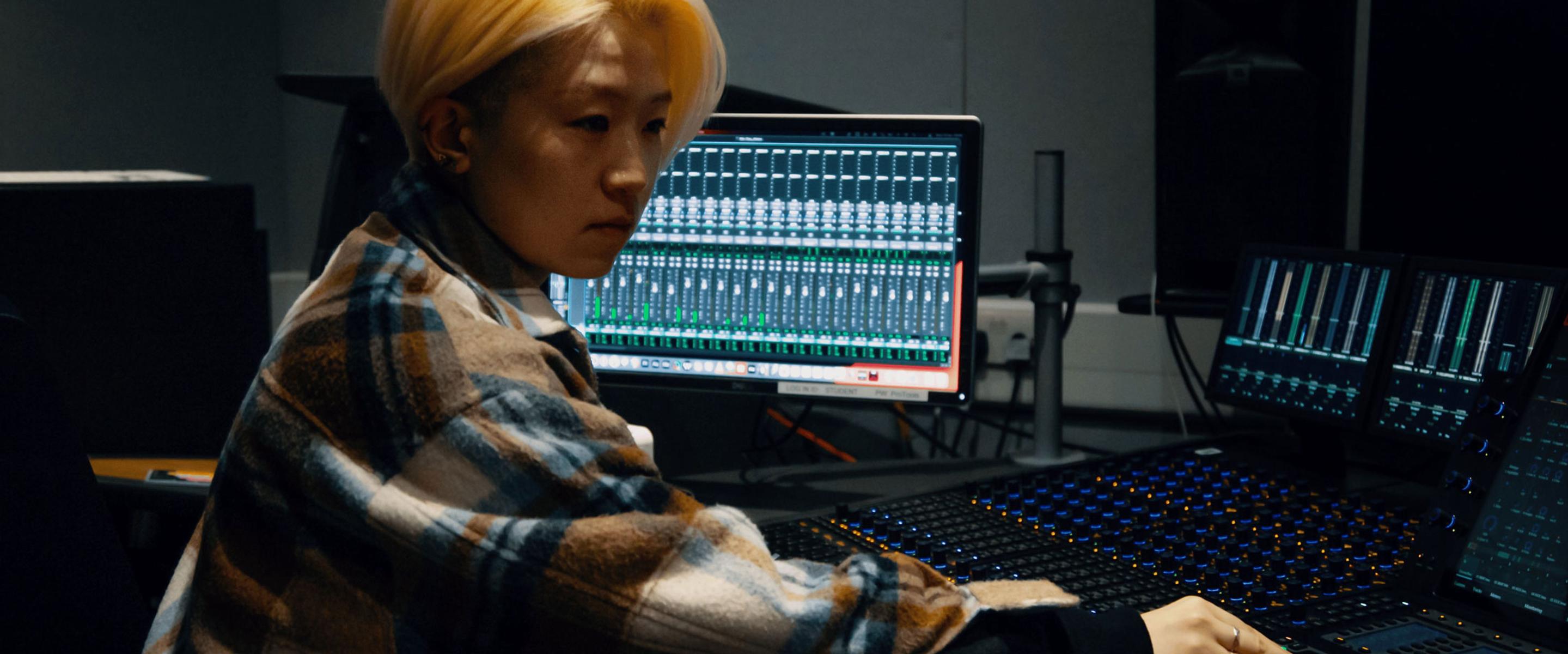 Student sat at audio mixing desk.