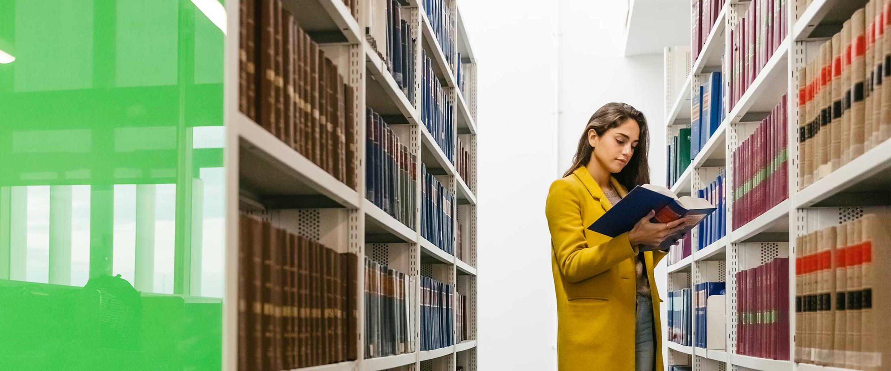 Female student stood in library looking at law books