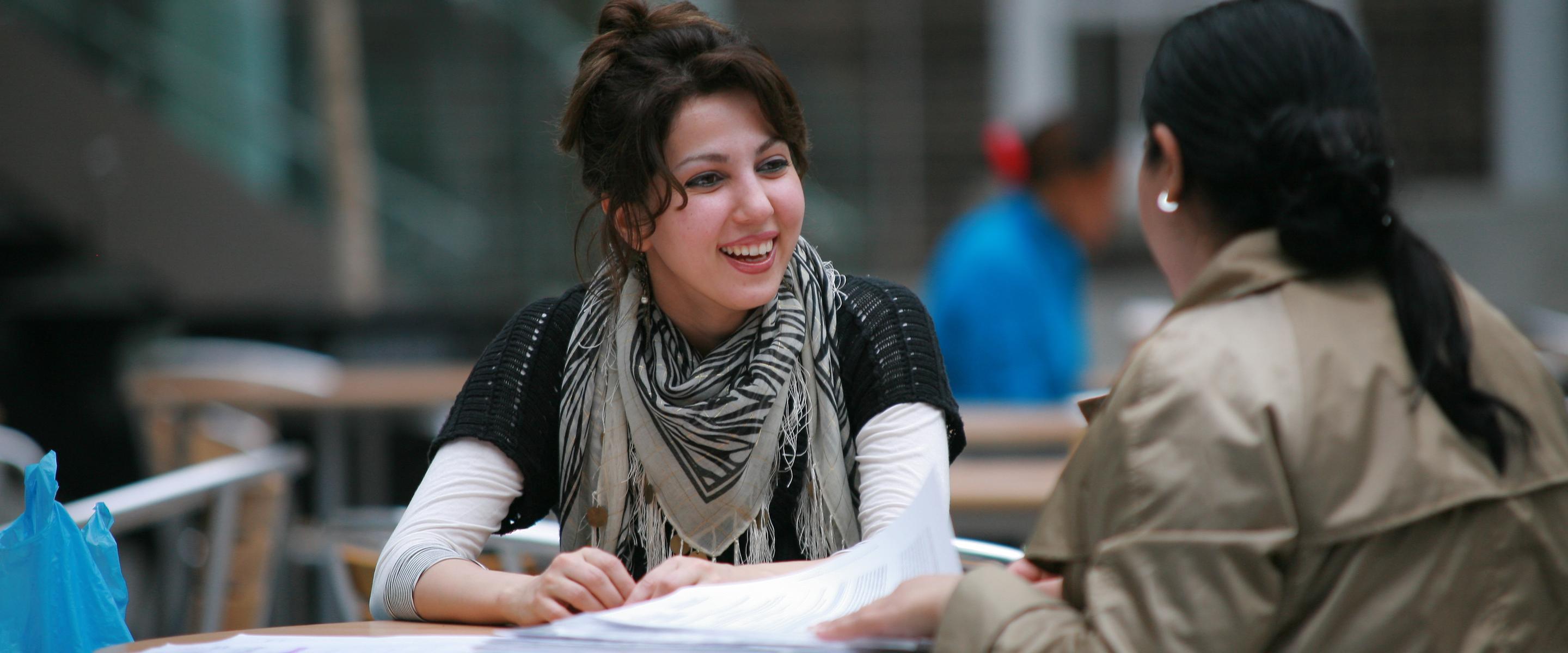 Two women sitting at a table, engaged in conversation and enjoying each other's company.