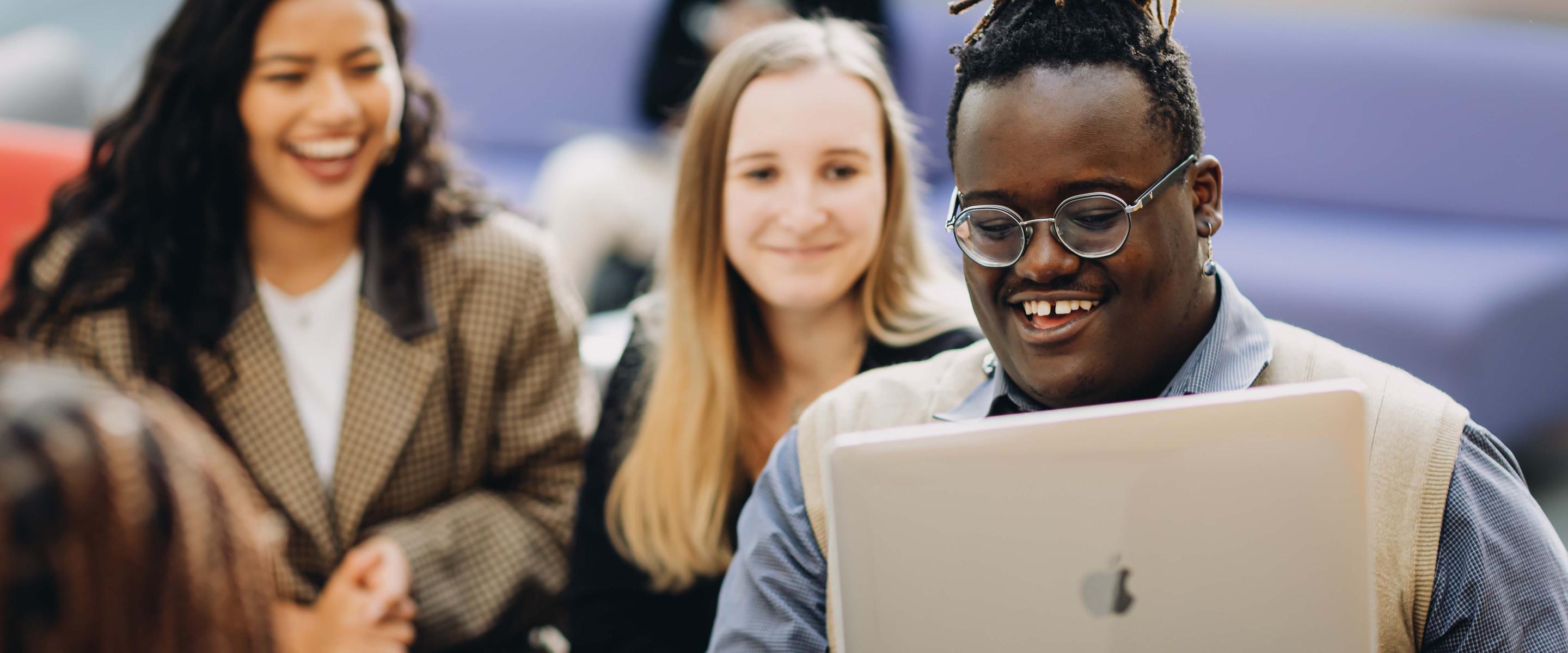 Three students looking at a laptop