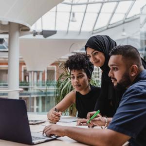 Business management students working on a computer at the quad