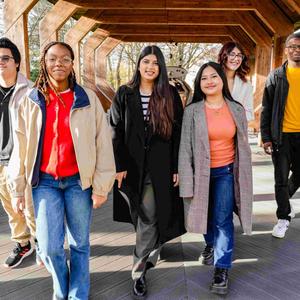 Six students walking together under a wooden structure
