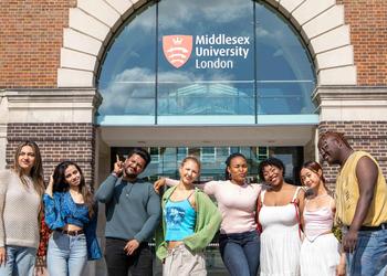 Students stood outside campus, with college building in the background.