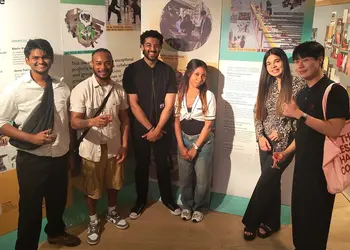 Students stand in front of posters of their designs that won awards.