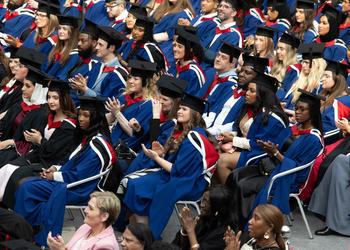 A crowd of graduating students sitting in their graduation robes and mortar boards