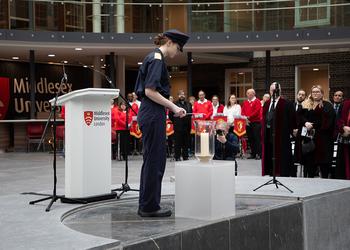 A cadet lights a candle at a memorial event