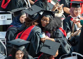 Two students hug during a graduation ceremony