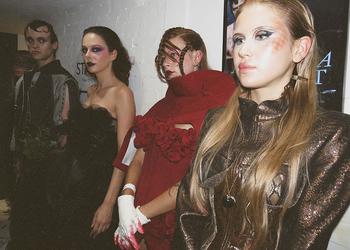 Three models stand together wearing pieces from a collection