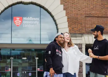 A group of students standing and laughing together outside Middlesex University entrance