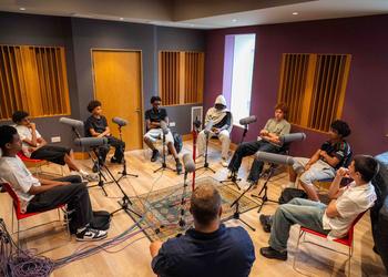 A group of male teenage students record a podcast as part of a project