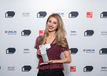 A young Middlesex graduate in a red top holding an award and smiling