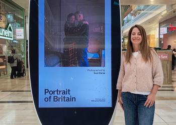 Woman stands next to billboard with image of couple