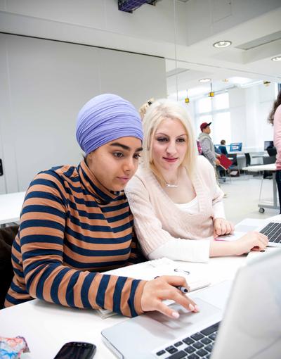 Two graphic design students working on a project on their laptop