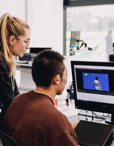 Two sports students looking at tennis on a computer