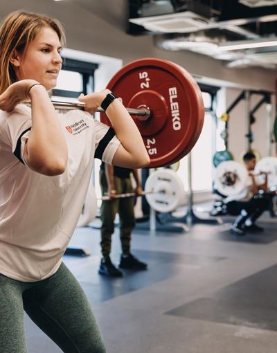 A woman lifting a barbell in a gym, showcasing strength and determination.
