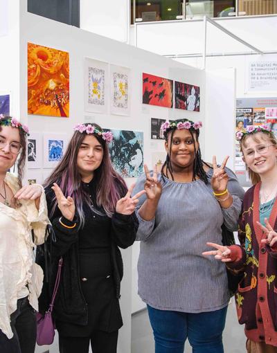 A group of art students stand in front of their work at an art show