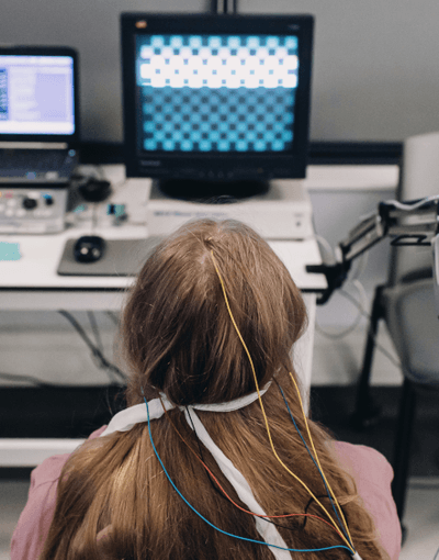 A woman sits at a computer with a robotic arm in a healthcare-science lab, demonstrating the integration of technology in medical research.