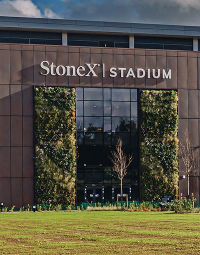 Large stadium exterior with grass and trees, stadium entrance says: Stone X Stadium
