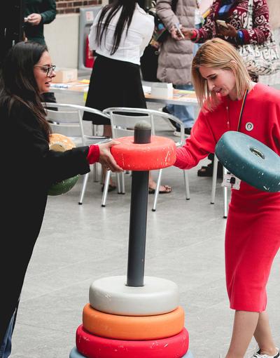 two people playing game with giant coloured hoops stacked on a pole