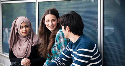 Three students on campus chatting.