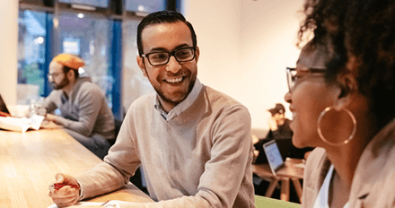 Two individuals sitting at a table, engaged in a discussion and laughter.