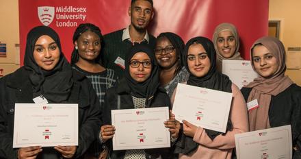 A diverse group of smiling young adults proudly holding up their certificates of achievement.