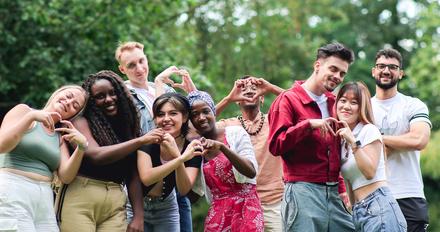 large group of happy students make heart shapes with their hands