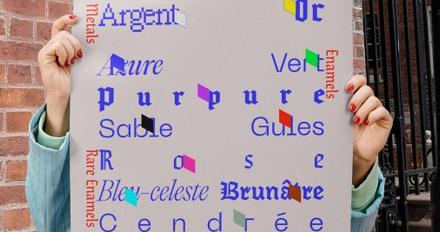 Someone holding up a sheet of a graphic design project, showing brand names in different blue fonts
