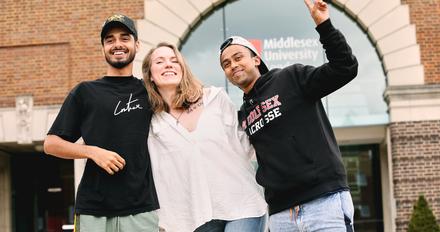 Three students stood together outside on campus