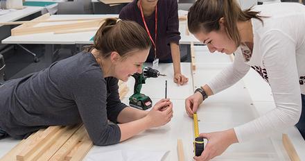 Young students female students measuring materials in a workshop