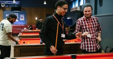 two students stand at pool table ready to play game