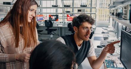 Three computing students looking at a computer monitor.