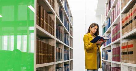 Female student stood in library looking at law books