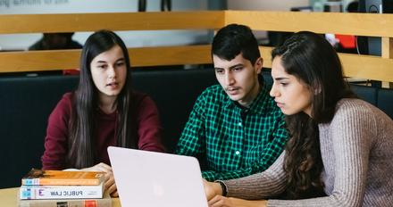 three students studying together in a library