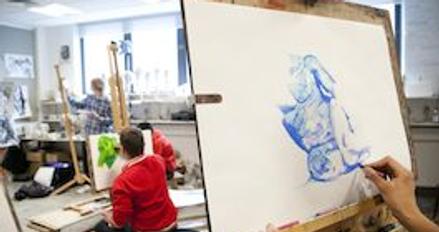 A student painting on an easel in an art class, showcasing their creativity and artistic skills.