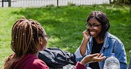 Three students studying at a table in the park