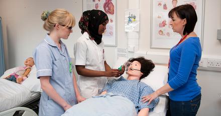 student nurses examining a dummy in class