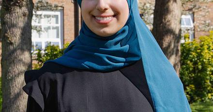 Duha stood on campus on a sunny day with campus building in background