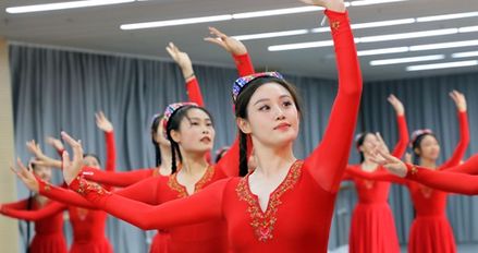 A group of Hainan students dressed in red dresses, dancing in a dance studio