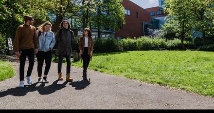 3 students walk together on middlesex university campus on a sunny day